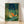 Japanese woodblock-inspired framed poster featuring a fox in a bamboo forest at night, with a glowing lantern and fireflies in deep teal, forest green, and gold tones creating a serene, magical atmosphere.