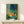 Japandi art print on wall showing a contemplative fox surrounded by bamboo stalks, lantern light, and floating fireflies in minimalist style with rich jewel tones and cream accents.