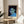 Minimalist pop art face portrait using a restrained palette of muted blues, greens, and blacks, framed and hung as a modern office art print.