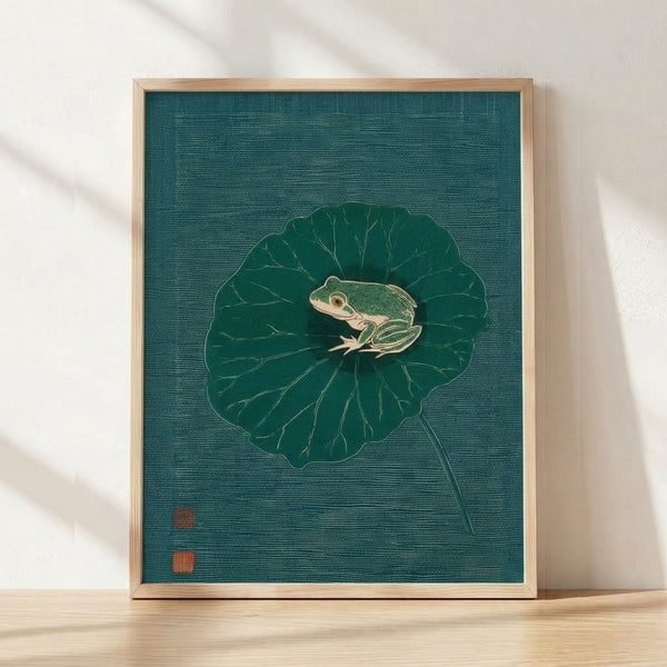 Serene Japanese woodblock-style art print depicting a teal frog perched on a forest green lotus leaf, rendered in fine line art with cream and gold accents, framed on a wall.