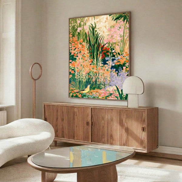 Tranquil botanical watercolor poster showing a bird among blooming lilies and garden plants in muted lavender, pink, and forest green tones, framed on wall.