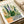 Delicate watercolor garden scene featuring sage green foliage and blooming wildflowers in various containers, rendered in warm creams and gentle purples with Japandi design sensibility.
