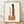 Abstract Bauhaus poster with stacked rectangular forms in sage green, terracotta, charcoal, and cream on an off-white background, framed on a wall.