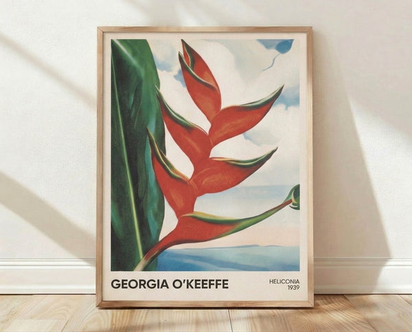 Framed vintage art print of Georgia O'Keeffe's sensual heliconia flower, rendered in deep red and forest green with cream and golden accents on a gallery wall.