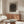 Contemporary abstract wall art with swirling wood grain imagery in soft neutral palette of beige, taupe, and warm brown, evoking calm introspection through organic minimalist design.