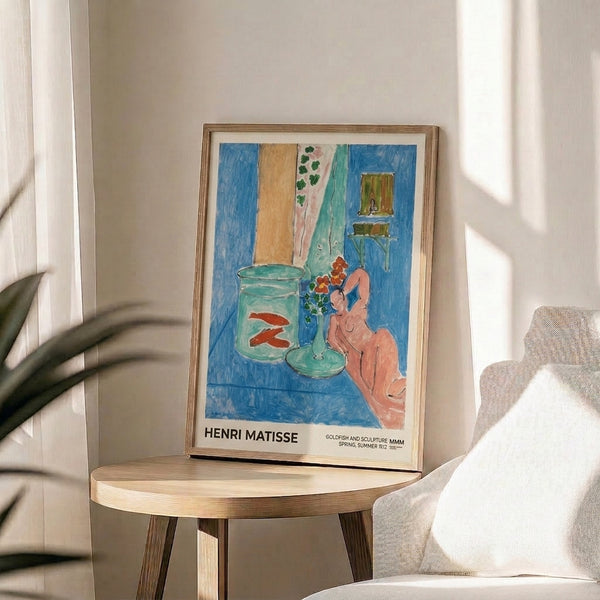 Modern wall art capturing a calm, introspective moment: goldfish in a bowl, female form, sculptural piece, and flowers rendered in Matisse's characteristic cerulean and ochre palette.