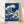 Hokusai's iconic woodblock print depicts a dramatic wave with white foam cresting over Mount Fuji, rendered in navy blue and cream tones with dynamic yet majestic energy.