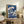 Classic Japanese woodblock artwork featuring a powerful ocean wave in deep indigo and white, with a serene snow-capped mountain visible in the background.