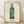 Pop art poster featuring a bold green Coca-Cola bottle rendered in vibrant emerald and white tones against a neutral background, exemplifying 1960s consumer culture commentary.