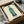 Stylized green beverage bottle rendered as a pop art print in emerald, white, and black tones, capturing mid-century commentary on mass culture and advertising.