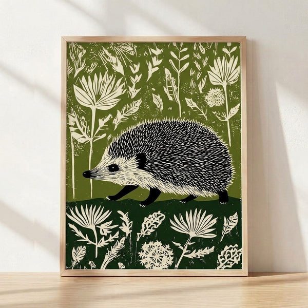 Linocut art print of a hedgehog nestled among wildflowers and botanical plants in olive green, cream, and black, framed on a wall with a peaceful, whimsical cottagecore aesthetic.