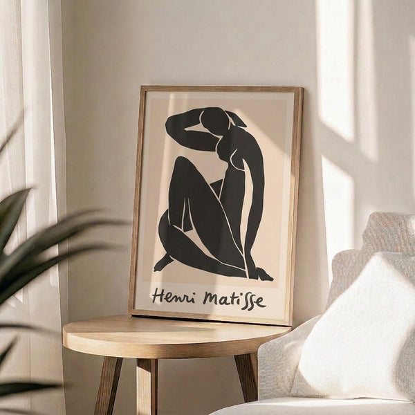 Elegant framed artwork of a seated woman rendered in minimalist black outlines and cut-out forms on warm cream paper.