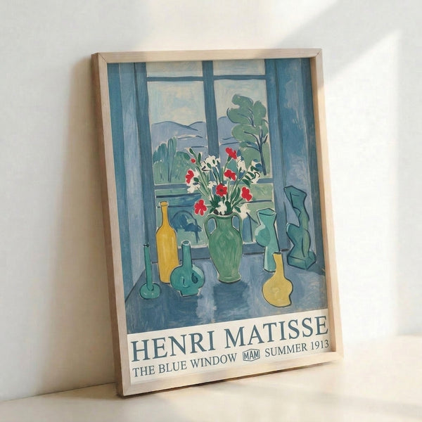 The Blue Window by Henri Matisse, a light-filled composition with bottles, flowers, and plants arranged on a table, executed in muted palette of navy, cream, and soft greens.
