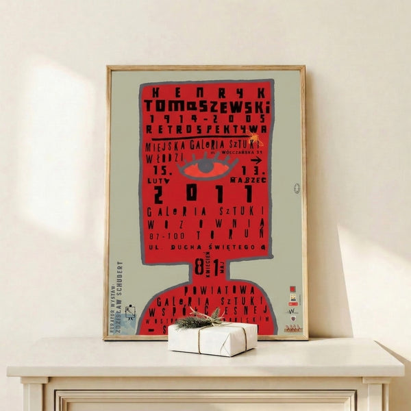 Retro Bauhaus-style art print with a geometric red eye and bold typography in gray and black, creating dramatic visual impact on a wall.