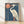 Elegant framed poster of a blue heron in Japanese woodblock style, featuring deep teal and cream tones with coral red spider lily flowers and sage green foliage.