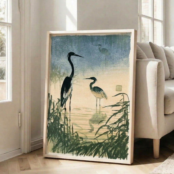 Contemplative art print on wall showing a lone heron wading through reeds in soft blues and greens, inspired by traditional Japanese woodblock techniques with a tranquil, naturalistic mood.