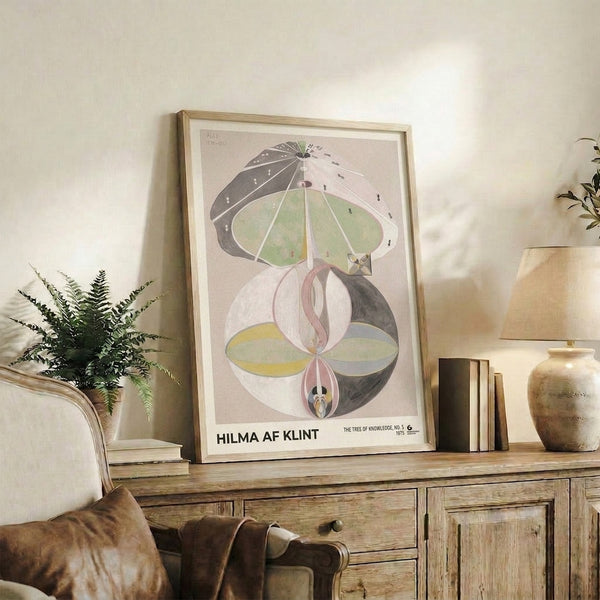 Minimalist framed artwork featuring abstracted floral and tree imagery in soft gray, pale yellow, and sage green tones with spiritual undertones.