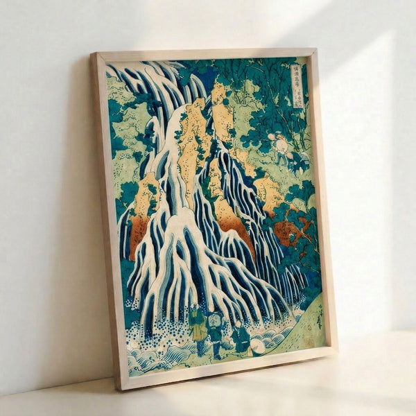 Framed Hokusai-style landscape print showing a dramatic waterfall amid towering cliffs and vegetation rendered in traditional woodblock technique with cool blue and warm yellow palette.