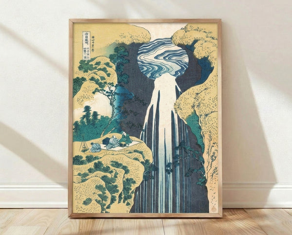 Japanese woodblock print depicting a majestic waterfall cascading down a rocky mountain, framed on a wall; serene landscape in cream, indigo, and teal tones.