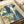 Majestic waterfall woodblock print featuring mountain scenery, travelers, and verdant slopes; framed poster in serene palette of indigo, teal, and cream tones.
