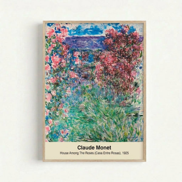 Framed art print of Monet's peaceful garden scene featuring a cream-colored house surrounded by rose bushes and lilies in delicate watercolor style.