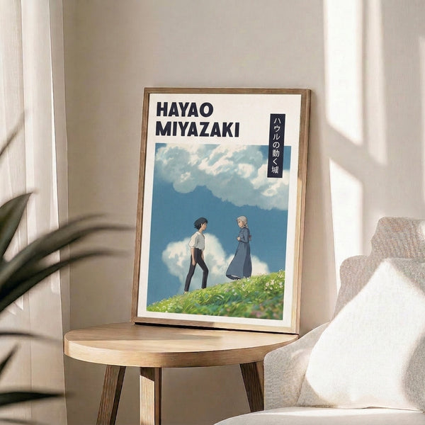 Poster displaying two figures on a windswept hillside overlooking valleys and cloud-covered peaks, rendered in Ghibli's signature soft palette of dusty rose, sage, and sky blue.