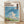 Whimsical framed poster of a dreamlike cloudscape with a moving castle nestled among soft white clouds, rendered in serene blues, creams, and coral tones in Ghibli art style.