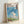 Studio Ghibli-inspired framed art print depicting a fantastical floating castle surrounded by billowing clouds and gentle landscape elements in dreamy sky blue and cream palette.