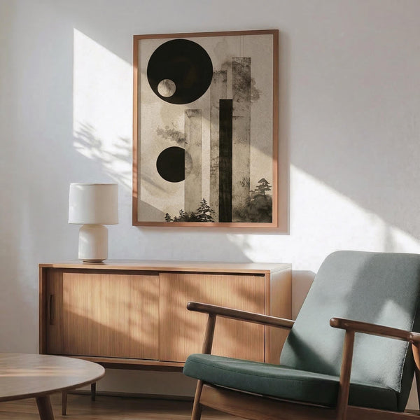 May include: Modern living room with sage green armchair, wooden sideboard, and white table lamp. Large framed abstract art print featuring black circles, geometric rectangles, and silhouetted pine trees in neutral beige and black tones. Natural sunlight creates dramatic shadows across white wall. Mid-century modern furniture with warm wood tones complements the minimalist artwork's organic and geometric elements.