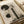 May include: Abstract art print displayed in open book or portfolio on cream colored surface. The artwork features muted beige and gray tones with dark forest green geometric shapes - two circles and vertical rectangular bars overlaying a misty landscape with silhouetted trees. The composition has a vintage, weathered texture with organic elements blending into modern abstract forms.