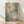 May include: Framed abstract expressionist artwork with soft blue, green, and cream watercolor washes, delicate line work, and white circular dots scattered throughout. The piece is displayed in a light wood frame, leaning against a white textured wall on blonde hardwood flooring with natural sunlight casting gentle shadows across the scene.