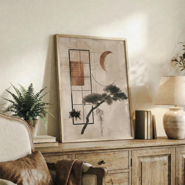 May include: Framed abstract artwork displaying geometric rectangles, crescent moon, and stylized pine tree in earth tones on neutral background, positioned on rustic wooden sideboard alongside fern plant, books, ceramic vase, and throw pillows in cozy living room setting with warm natural lighting.