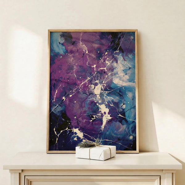May include: Framed abstract art print with purple, blue, and white splattered paint effect and lightning-like gold veining, displayed on light wood mantel beside white gift box with evergreen sprig. Artwork features cosmic nebula-inspired swirling colors in thin natural wood frame against cream wall.