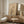 May include: Minimalist framed poster featuring bare tree silhouette with geometric beige circles and small red dot on cream background, displayed on wood sideboard next to ceramic table lamp in neutral-toned room with modern chair and white door