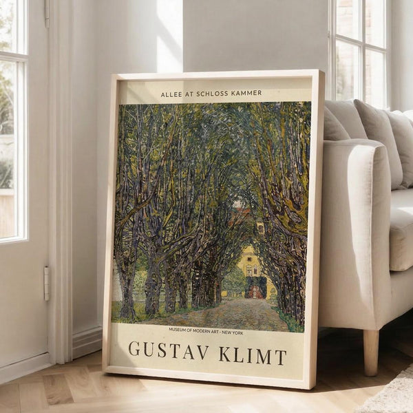 May include: Framed art print featuring Gustav Klimt's tree-lined pathway painting in golden and green tones, displayed against white walls near a beige sofa with natural lighting from large windows creating soft shadows on light wooden floors.