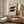 May include: Framed Bauhaus poster with black geometric circles arranged in two rows on cream background, displayed on wooden sideboard next to ceramic table lamp in minimalist living room with neutral tones, white chair, and natural lighting creating soft shadows on textured walls.