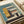 May include: Vintage-style architectural poster featuring a modernist building illustration in muted teal, mustard yellow, coral, and cream colors. The geometric design shows a multi-story structure with horizontal window bands and clean lines, numbered "02" with "FORM FOLLOWS FUNCTION" text at bottom. Print displayed on white paper against cream fabric backdrop with soft natural lighting.