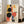 May include: Large framed abstract geometric artwork in Bauhaus style featuring black circles, orange and red shapes, blue rectangles, and yellow elements on cream background, displayed in bright living room with beige sofa, white walls, and natural light from windows