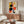 May include: Abstract geometric poster with colorful circles, rectangles and lines in yellow, orange, red, black and blue displayed above a wooden sideboard in a modern living room with white curved chair, round glass coffee table, and mushroom-style table lamp creating warm natural lighting