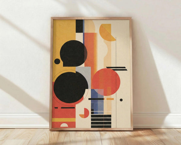 May include: Framed abstract geometric artwork leaning against white wall on light wood floor. Features bold black circles, coral and orange shapes, blue rectangles, and cream background in Bauhaus style. Natural wood frame with warm sunlight casting diagonal shadows across white textured wall.
