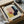May include: Framed Bauhaus-style abstract art print with geometric shapes in pink, yellow, navy blue, and teal colors on cream background, displayed in black frame inside cardboard shipping box with protective tissue paper wrapping