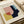 May include: Abstract geometric art print in wooden frame featuring overlapping shapes in pink, yellow, navy blue, and light blue with "BAUHAUS" and "Exhibition Art 1919" text. Frame sits against neutral backdrop with rolled paper tube beside it, showing vintage-inspired modernist design with clean lines and bold color blocks.