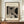 May include: Framed Bauhaus-style art print with geometric black and beige shapes and line patterns, displayed on wooden sideboard next to white ceramic vase and stacked books in neutral-toned room with white paneled walls