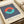 May include: Vintage-style Bauhaus exhibition poster print displayed on cream-colored paper with rolled paper tubes nearby. Features bold navy and white vertical stripes with overlapping coral and turquoise circles creating an oval shape. Text reads "BAUHAUS Exhibition Art 1923" below the geometric design. Minimalist mid-century modern aesthetic with clean typography on textured beige background.