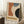 May include: Framed abstract geometric poster with curved orange, blue, and black shapes on cream background, displaying "BAUHAUS" text and "JUNE 17, 1921" date. Wooden frame leans against white wall beside coffee cup on wooden block and textured throw blanket on white fuzzy rug.