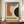 May include: Framed Bauhaus-style abstract art poster displaying geometric shapes in rust orange, navy blue, cream, and black with "JUNE 17, 1921" and "BAUHAUS" text, positioned on wooden credenza beside white ceramic vase and books in elegant room with white paneled walls