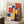 May include: A framed Bauhaus poster from 1922 featuring geometric shapes in primary colors - red, blue, and yellow rectangles arranged in an abstract composition against a cream background. The poster leans against white paneled walls in a cozy room setting with a white coffee cup on a wooden surface and textured beige throw blanket visible in the frame.