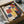 May include: Framed Bauhaus exhibition poster from 1922 featuring geometric rectangular shapes in red, blue, and yellow arranged in an abstract composition. The vintage-style poster displays "BAUHAUS" and "1922" text on cream background. Shown in black frame inside cardboard shipping box with protective tissue paper wrapping on wooden surface.