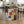 May include: Geometric abstract art poster with colorful rectangular shapes in red, blue, yellow, and orange displayed on wooden floor against dining table in modern kitchen. Poster shows Bauhaus typography and 1922 date on cream background. Room features wooden table with hairpin legs, woven dining chairs, white kitchen cabinets, and natural lighting from windows.
