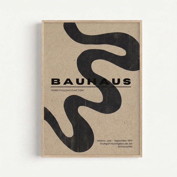 A minimalist poster with flowing black abstract shapes on beige textured paper, featuring bold "BAUHAUS" text and the phrase "FORM FOLLOWS FUNCTION". The design includes curved, serpentine forms that create negative space throughout the composition. Text at the bottom references "Weimar Juni - September 1919 Stuttgart Kunstgeboude am Schlossplatz". The poster is displayed in a thin light wood frame against a white wall.